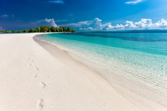 how to save money on spring break travel sandy beach with footprints