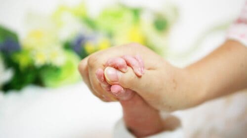 items in a midwife's bag-mom holding newborn's hand