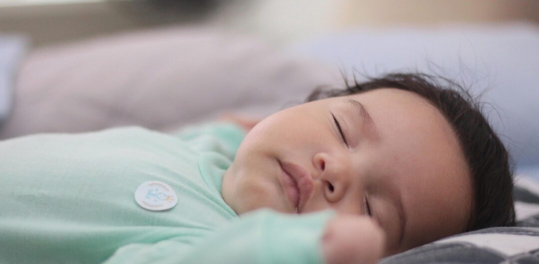 Helping Baby Sleep Longer - Close Up on Baby Sleeping in Green Onesie