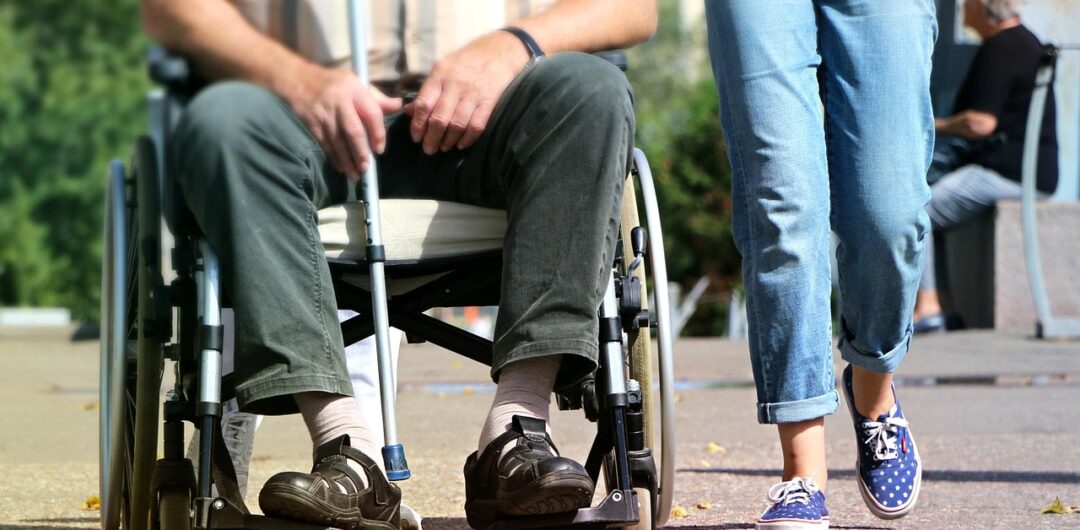 How to Travel with Someone in a Wheelchair? 6 How to Travel with Someone in a Wheelchair - A Person Walking Besides Someone in a Wheelchair