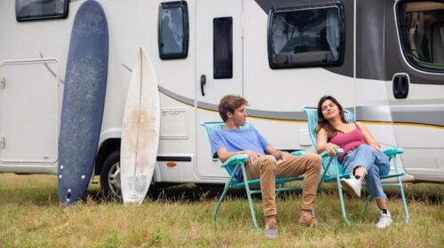 How to Choose the Right RV Park For Your Next Getaway - Couple Relaxing in Front of RV Going on an RV Trip for the First Time? Here's What you Need to Know